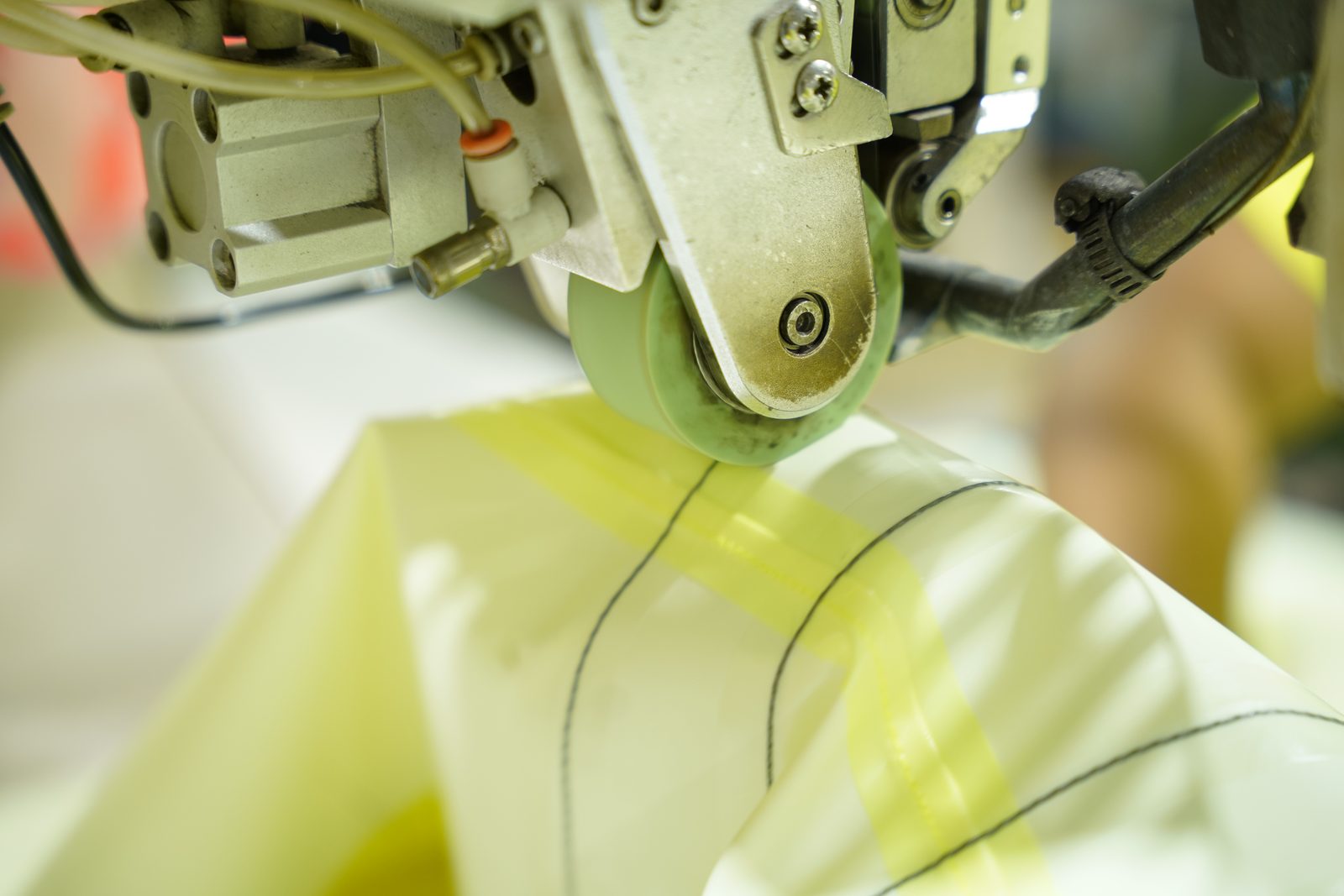 Coated fabric passing through the seam sealing machine. The coating decides whether the tape bonds.