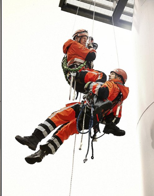 Two technicians in protective clothing working suspended at height